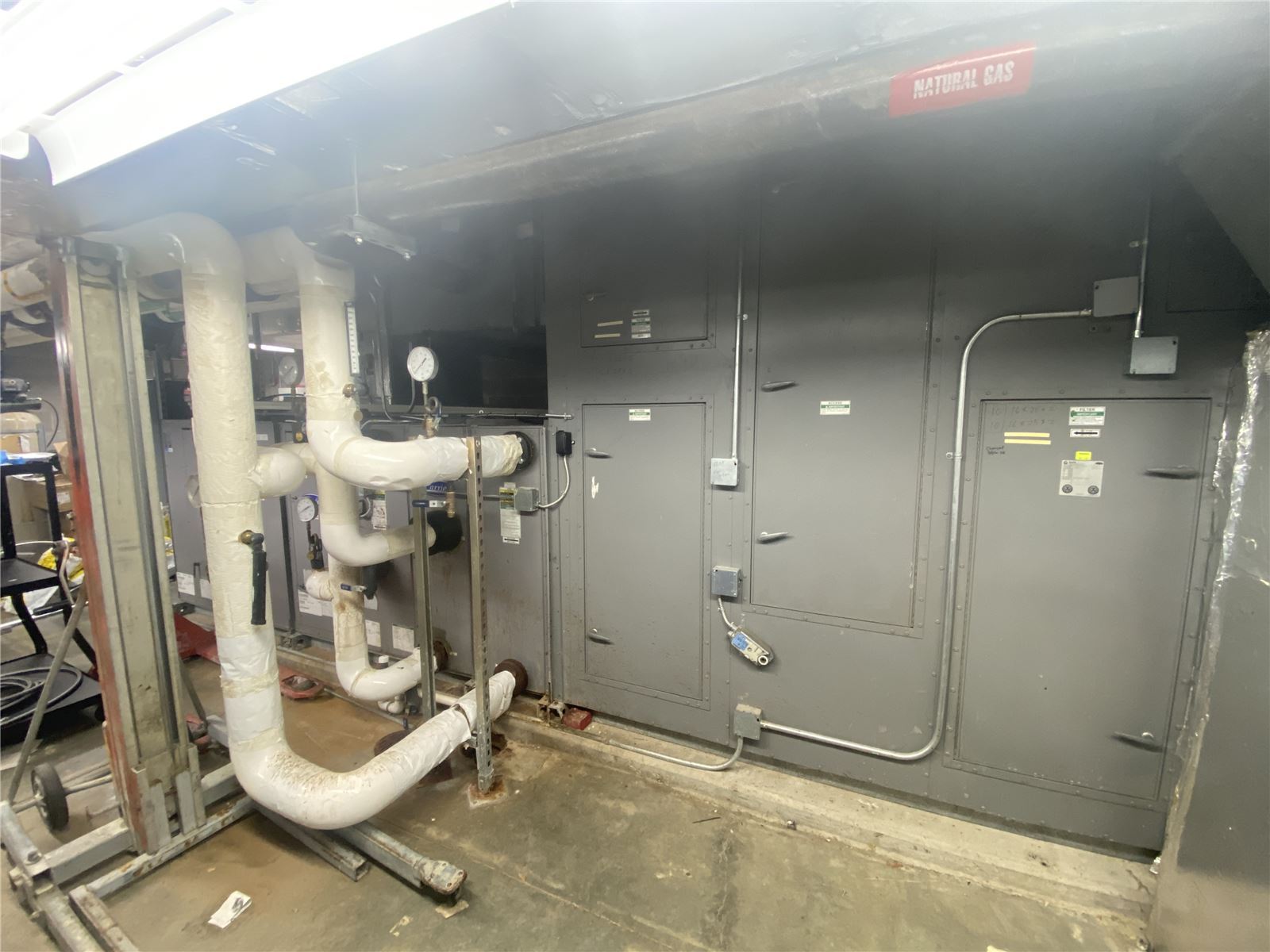 Commercial HVAC air handler and insulated piping in a mechanical room