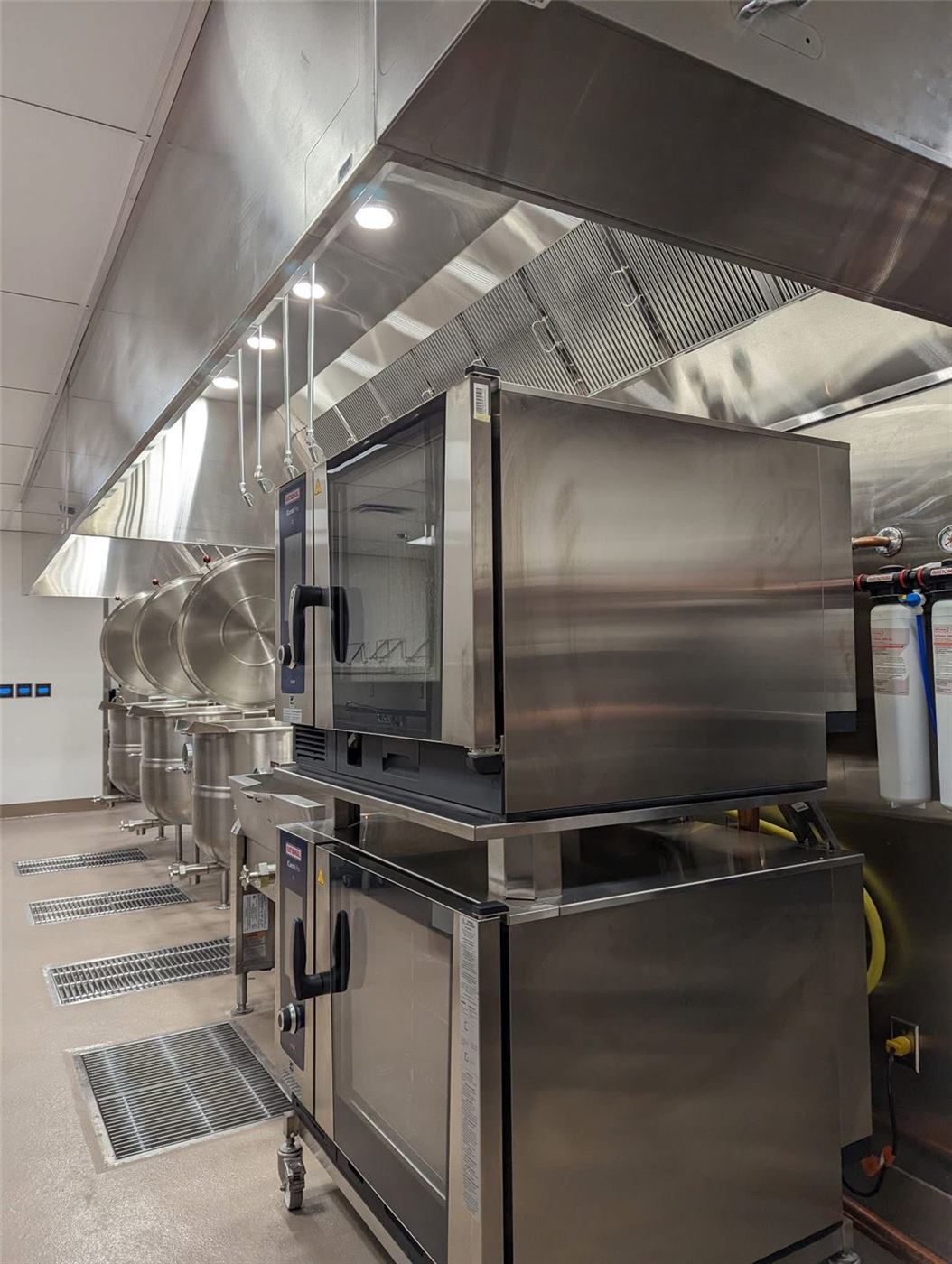 New commercial kitchen line with exhaust hood and stacked ovens