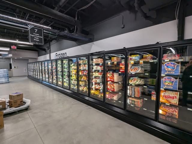 Row of glass-door reach-in freezers stocked in a grocery aisle