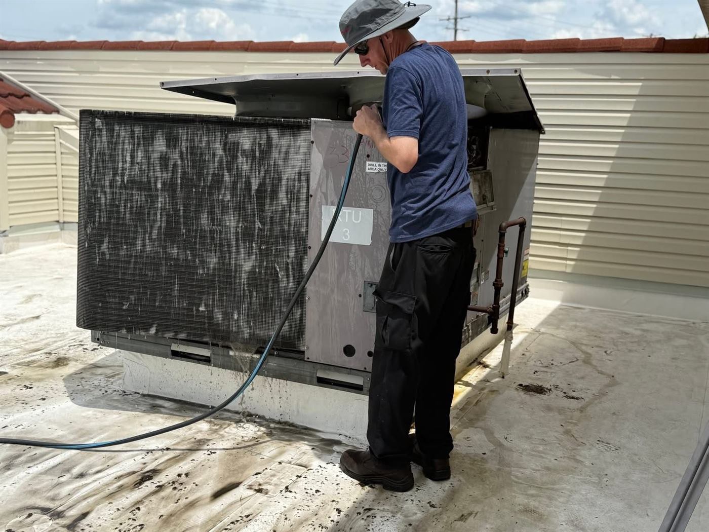 Technician washing a rooftop condenser coil