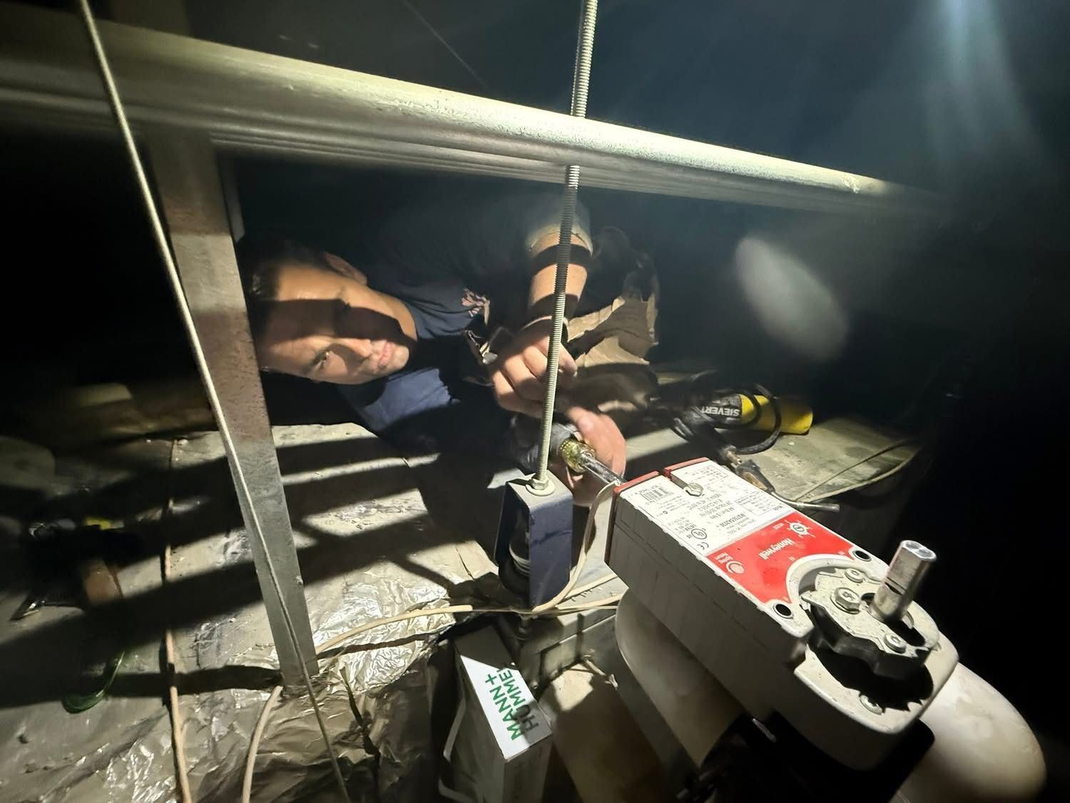 Technician working in a tight mechanical crawl space